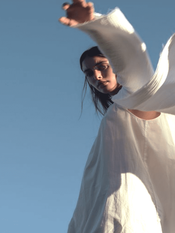 Woman outdoors reaching upward under blue sky, symbolizing patient-centered innovation and future of clinical research
